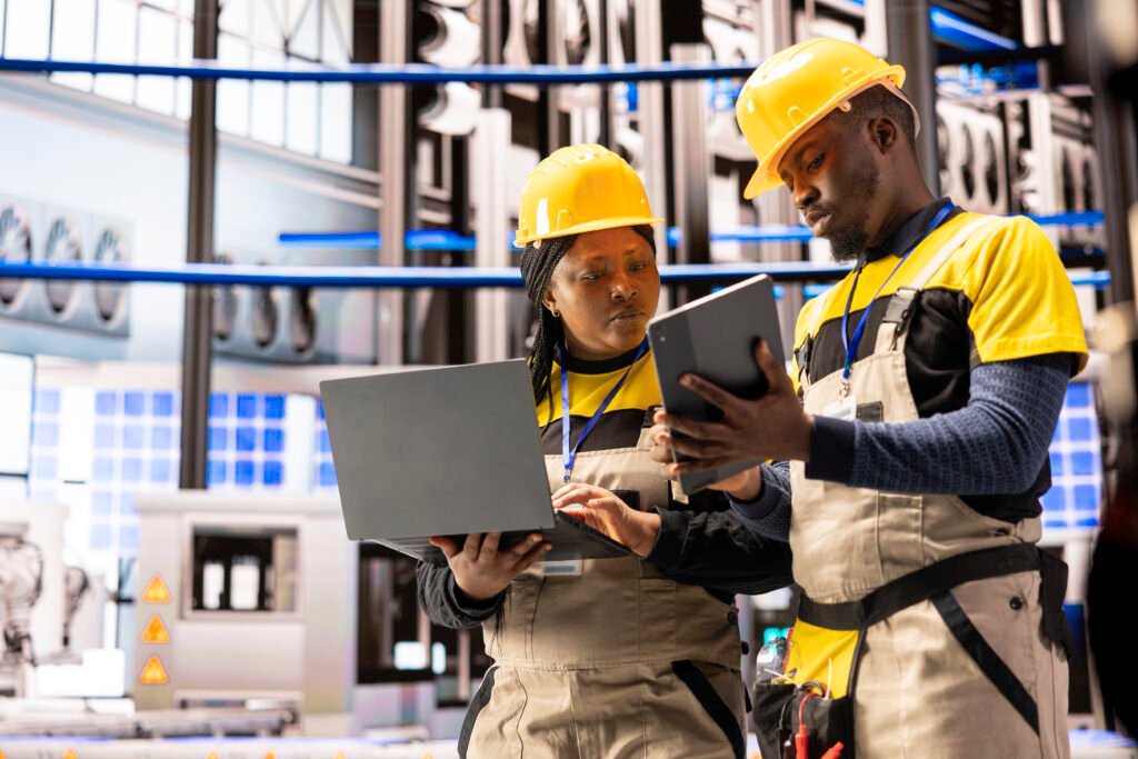 Techniciens industriels avec casques de sécurité consultant une tablette en usine